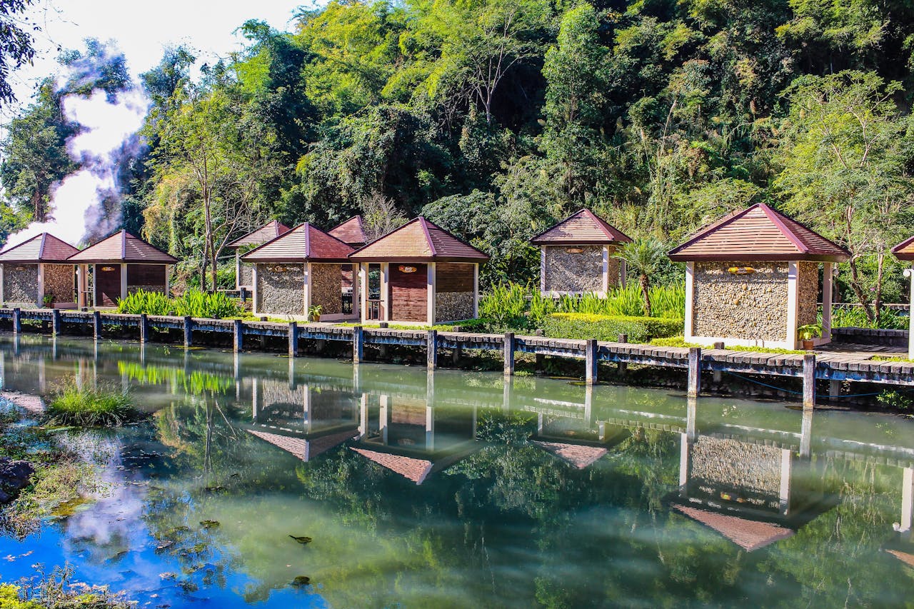 Serene lakeside cottages surrounded by lush greenery reflected in calm waters.